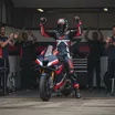 A Trackhouse Aprilia rider celebrates a strong result with his team in the pit garage.