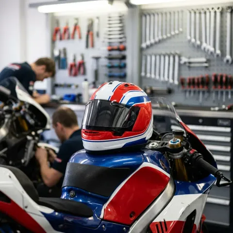 Illustration for our Honda story: a helmet rests on the fuel tank of a MotoGP bike in a garage.