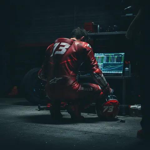 A MotoGP rider studies a timing screen in his pit garage, reflecting the strategic importance of the Practice session.