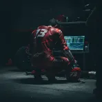 A MotoGP rider studies a timing screen in his pit garage, reflecting the strategic importance of the Practice session.