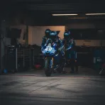 A Yamaha MotoGP bike being wheeled back into the pit box by team staff during a race, signifying a retirement.