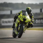 A rider on a yellow and black MotoGP race bike brakes heavily into a corner during a race.