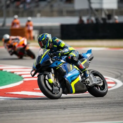 A helmeted MotoGP rider dives down the inside of a rival into a tight hairpin corner.