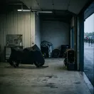 Illustration for our Australian GP news story: a covered racing motorcycle standing parked in a quiet pit garage.