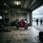 Illustration for our rider illness story: an empty pit garage with a lone racing bike on stands