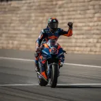 A MotoGP rider celebrates winning the Aragon Sprint race as he crosses the finish line.