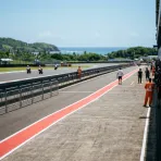 Illustration for our Indonesian GP Sprint story: the parc ferme area next to the pit lane under bright tropical sunlight.
