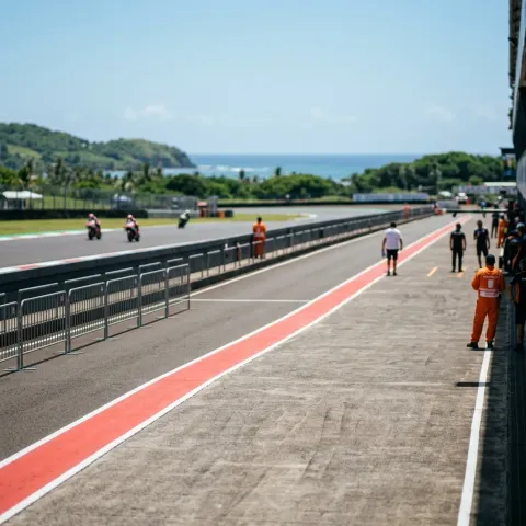 Illustration for our Indonesian GP Sprint story: the parc ferme area next to the pit lane under bright tropical sunlight.