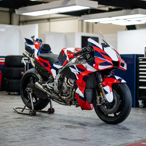 Five different MotoGP motorcycles from various manufacturers are lined up in a row in the pit lane, showcasing their unique designs.