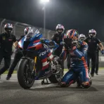 A MotoGP rider celebrates victory with his Trackhouse Racing team at the British Grand Prix.