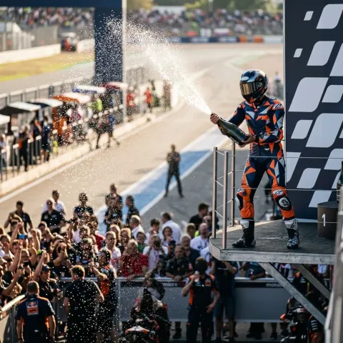 The top three MotoGP riders celebrating exuberantly on the podium by spraying sparkling wine over each other.