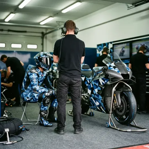 A MotoGP crew chief and rider deep in conversation in the pit lane, working together to find the perfect bike setup.