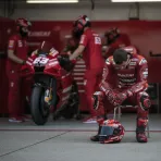 A disappointed MotoGP rider sits in his team's pit garage.
